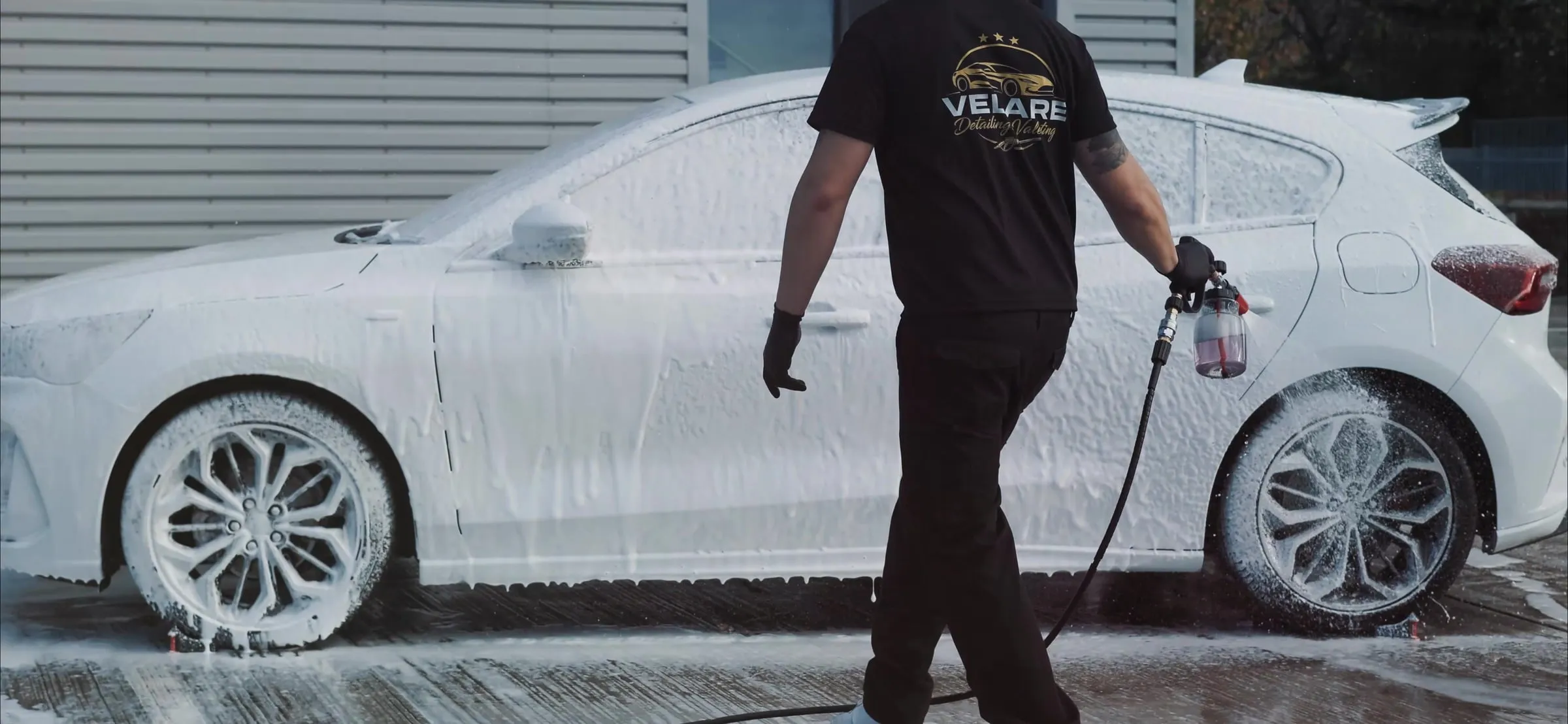 Velare detailer applying snow foam to a white Ford Focus